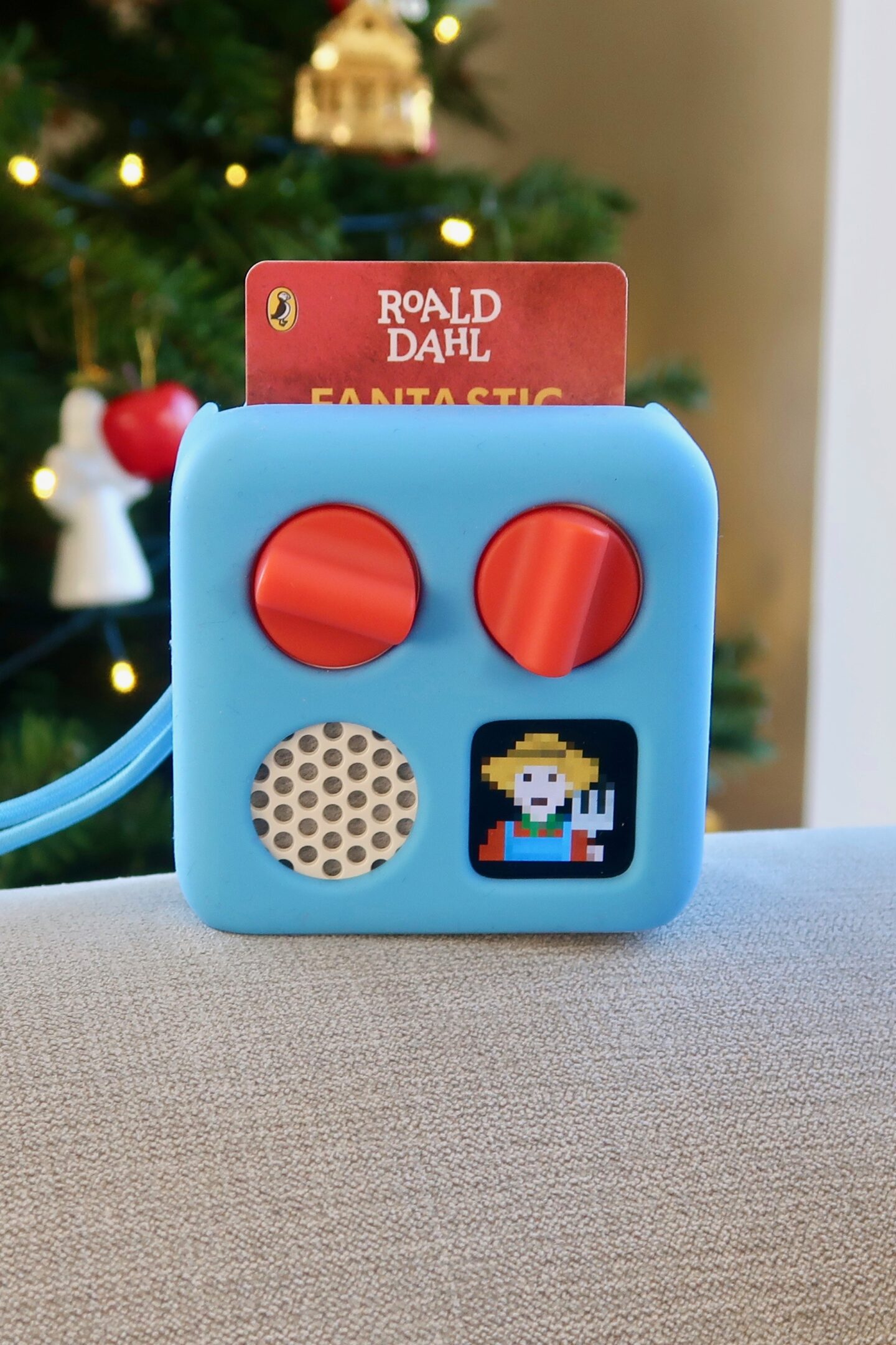 A yoto mini in a blue adventure jackets. It has a Fantastic mr Fox card in the player.