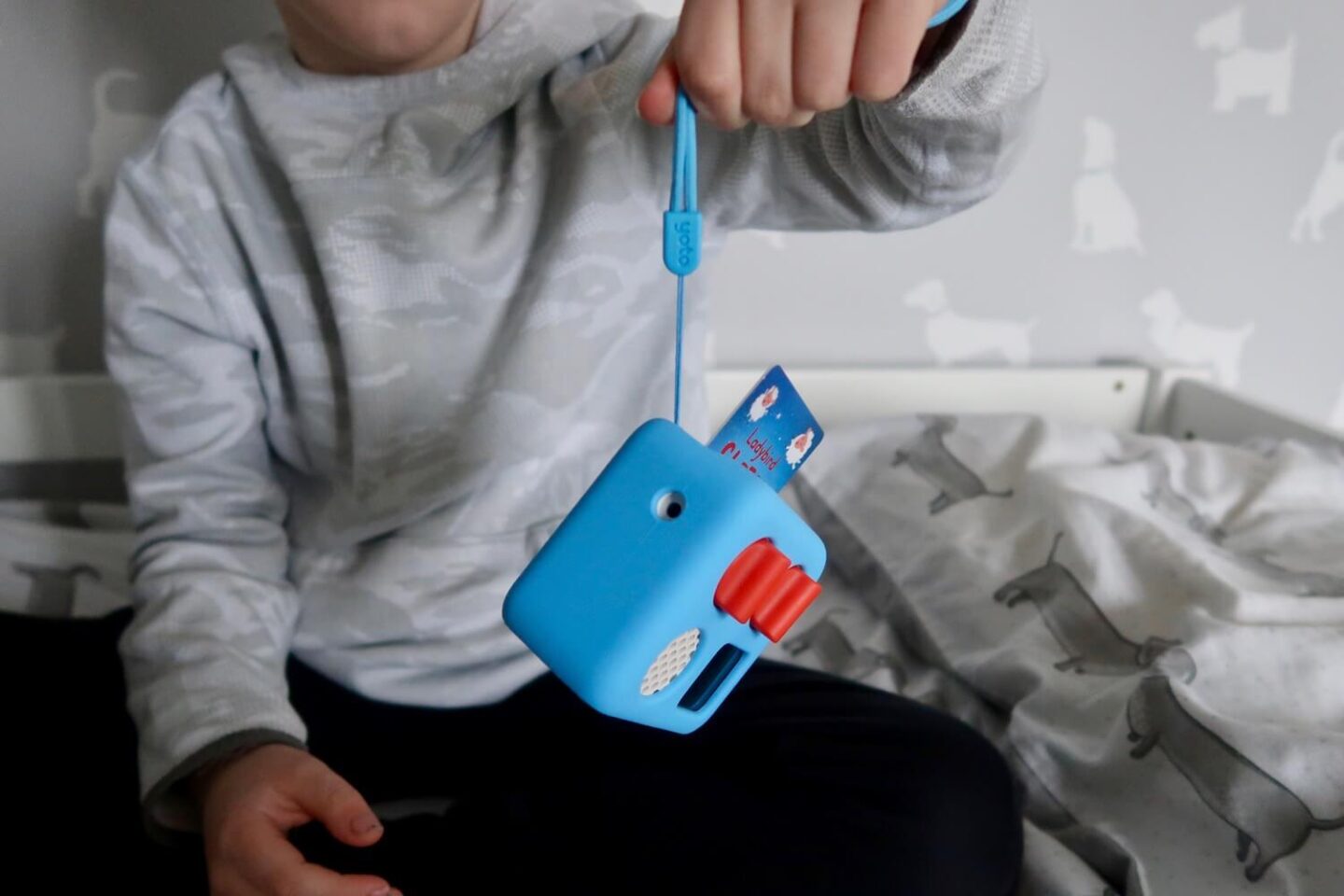 A boy holding up a yoto player by the wrist strap