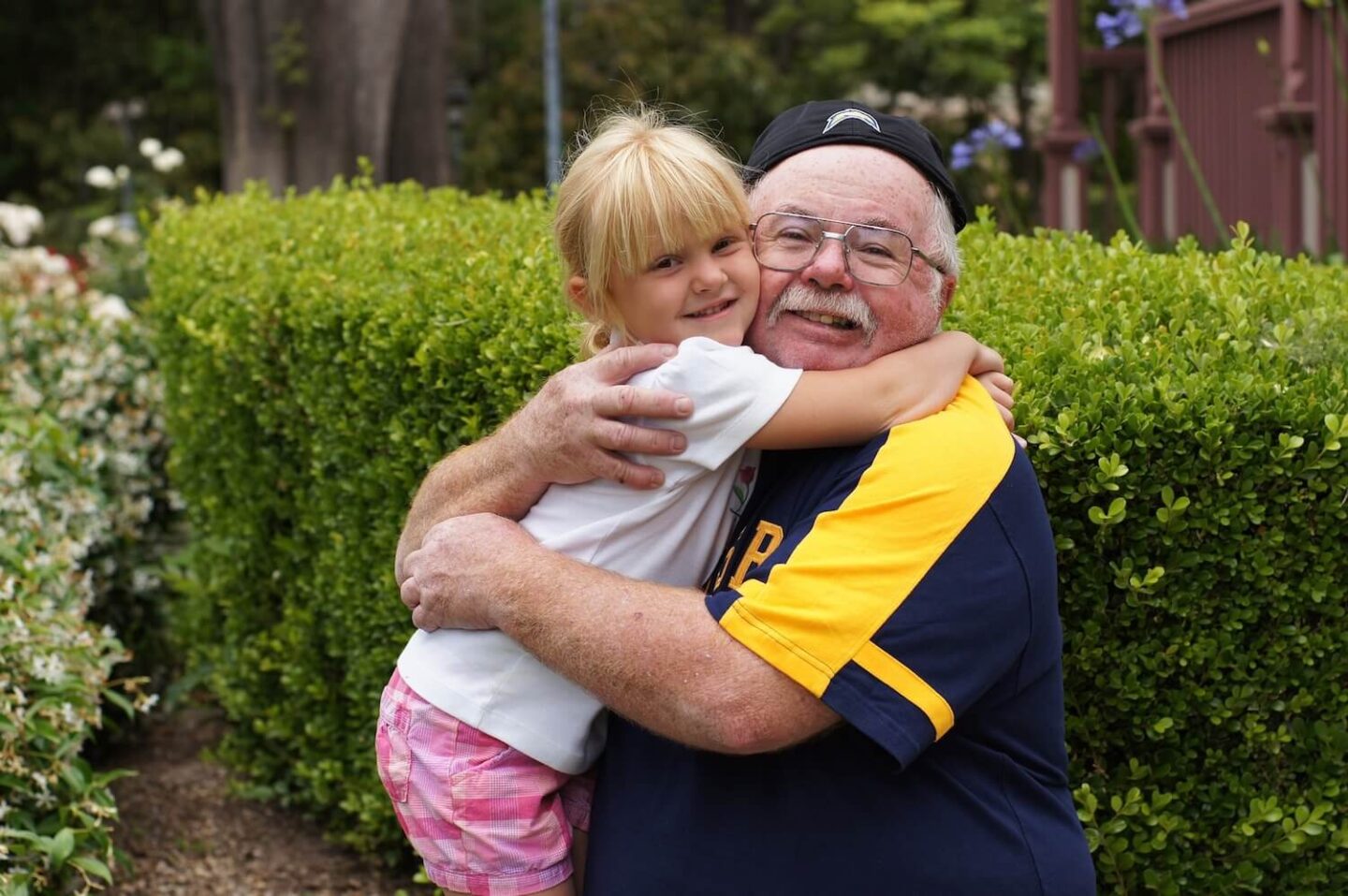 A little blonde girl hugging her grandfatehr