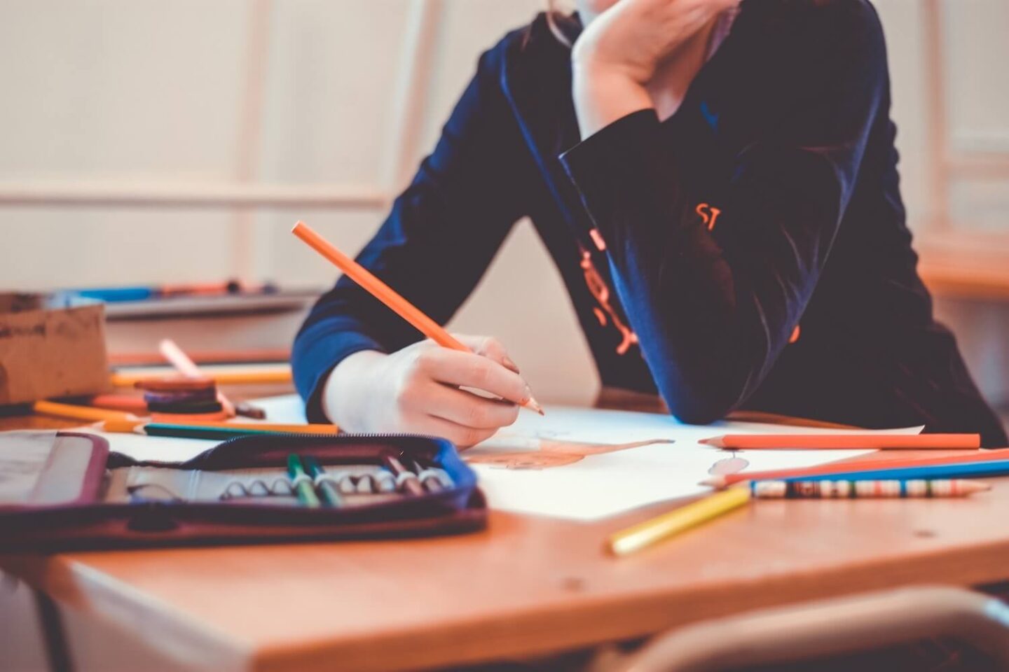 A person sitting at a table and colouring in a picture