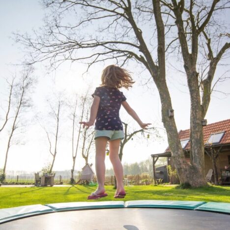 A girl jumping on a trampoline outside