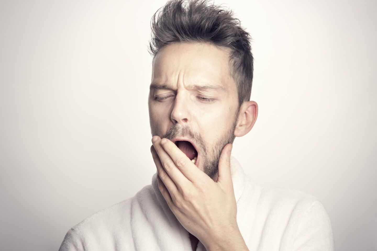 A man with yawning with his hand up to his mouth.
