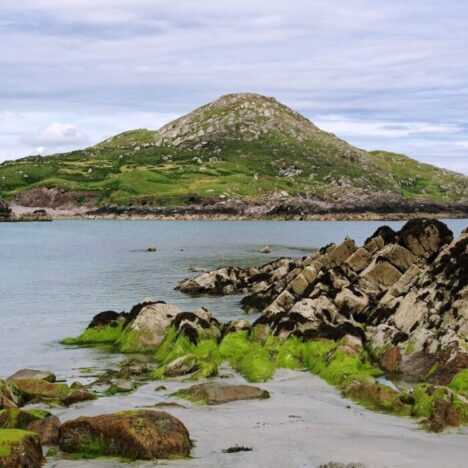 The coastline in Ireland. A hill and rocks surrounded by water
