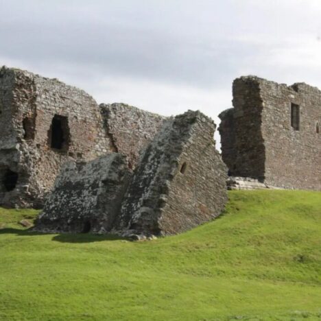 A grassy hill with stone ruins