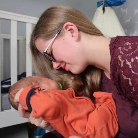 A woman lifting her newborn baby up towards her face