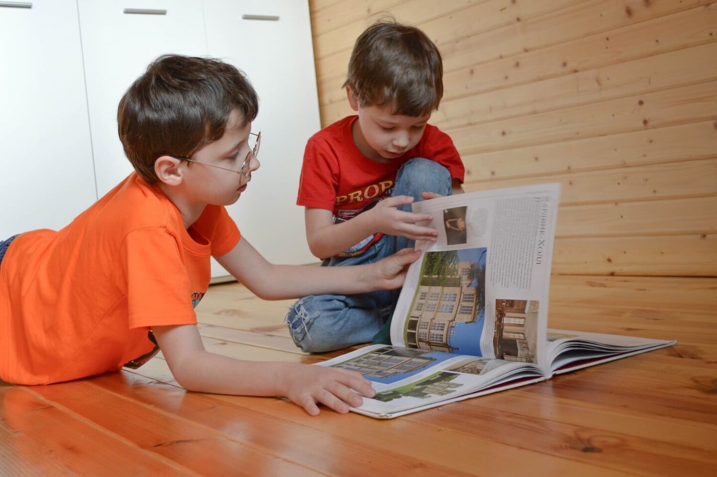 2 boys on the floor reading a textbook