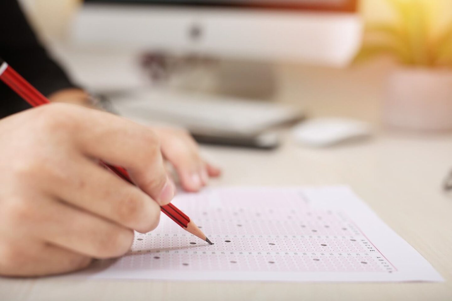 A hand holding a pencil and marking answers on an exam paper