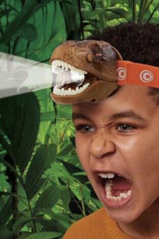 A child wearing a headtorch shaped like the head of a T-rex. The boy has his mouth open and face scrunched up like he is roaring