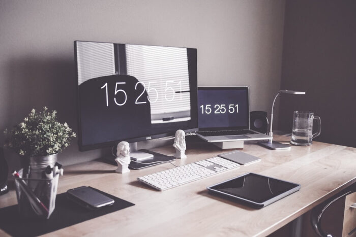 A home office set-up with a desk, laptop, keyboard, notepad etc