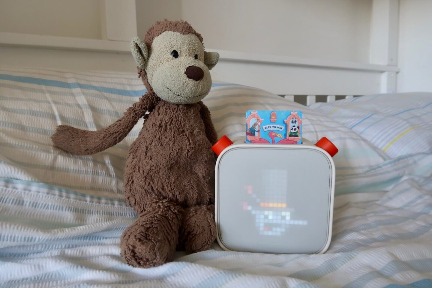 A Yoto player on a bed with a stuffed monkey toy