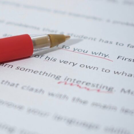 A red pen lying on a piece of paper with text on it