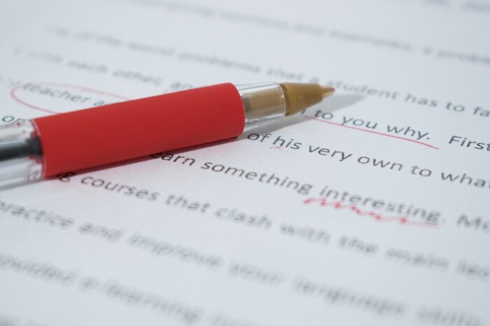 A red pen lying on a piece of paper with text on it