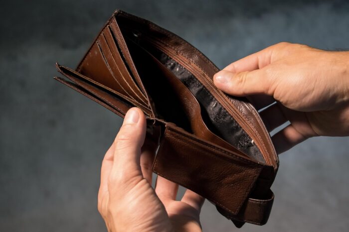 A person holding an empty brown wallet open