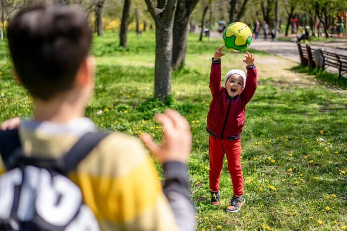 Children playing with a ball in a park with trees