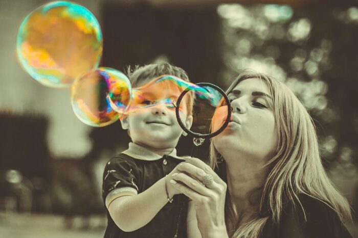 A mother blowing bubbles with her young son