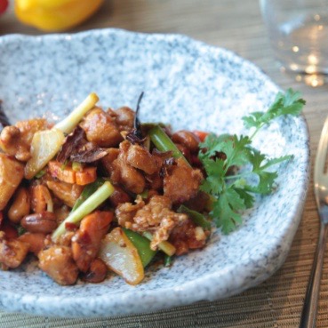 a blue and white dish with a meal of chicken and vegetables in it
